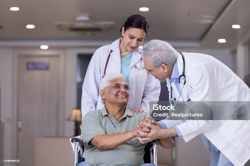 Doctors comforting disabled elderly patient at hospital